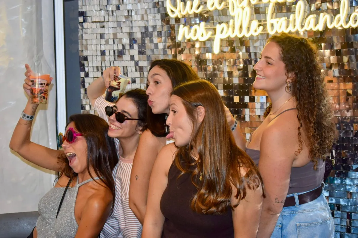 Grupo de amigas brindando frente a la pared de lentejuelas y el neón en La Gran Verbena, Son Fusteret