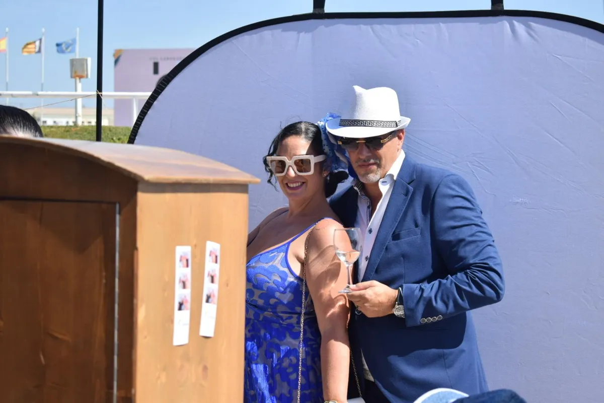 Pareja con sombrero y gafas posando junto al fotomatón en Chapeau Sa Roqueta